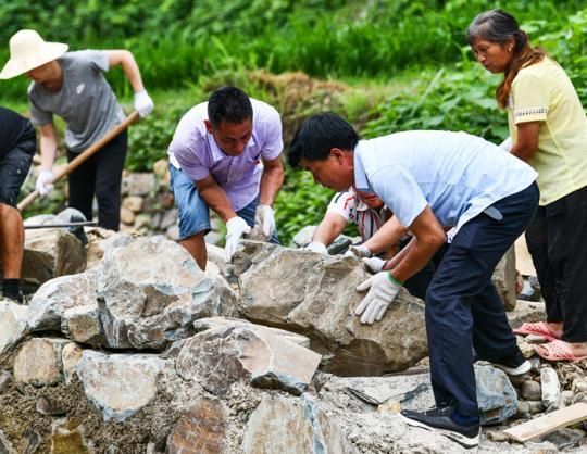 贵州省黔东南州剑河县老党员杨精泽（前右）与帮扶干部、村干部、村民在台沙村共筑防洪堤（2020年6月29日摄） 杨文斌摄/本刊